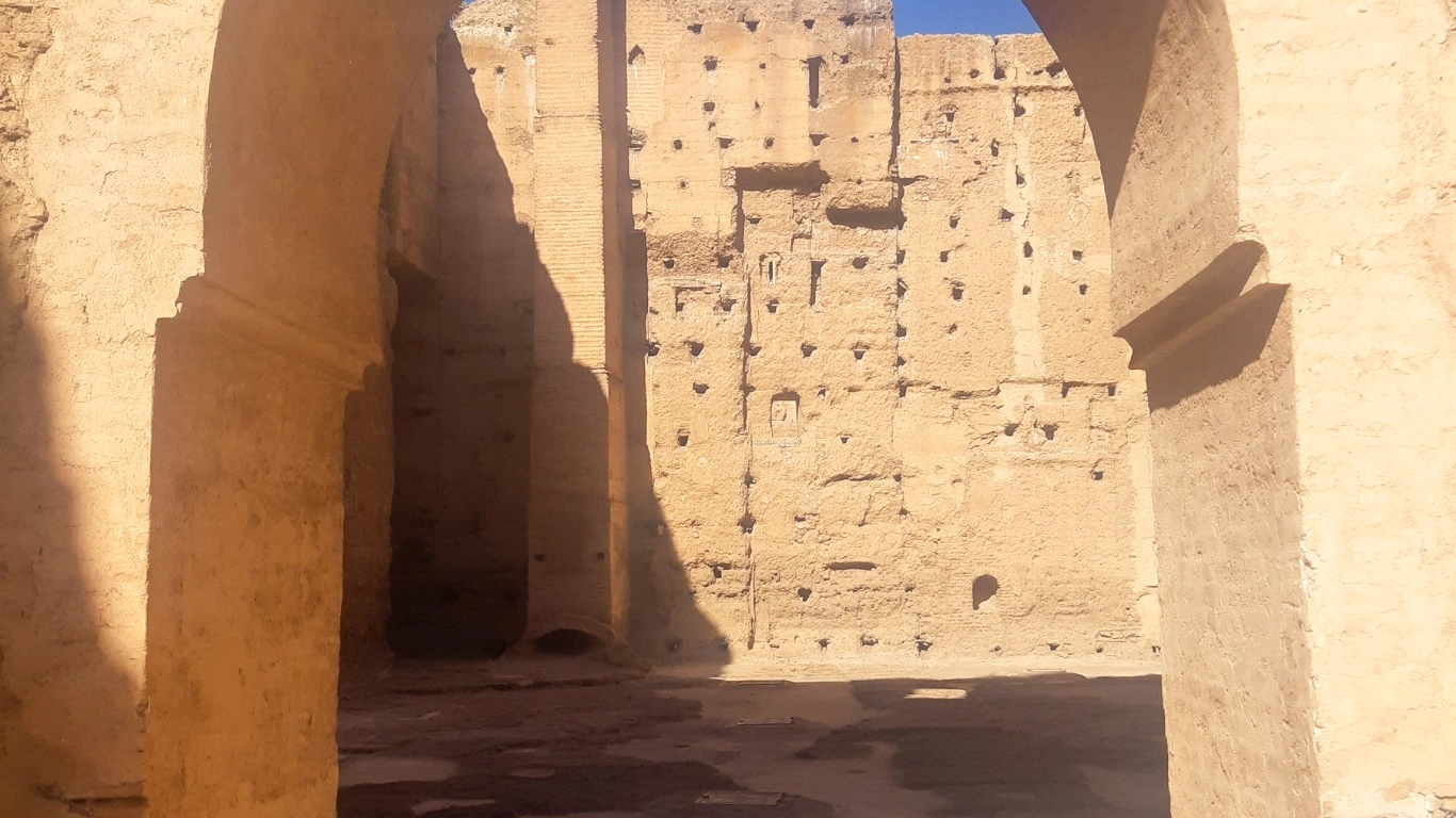 Sunlit arches and ancient stone walls inside the historic El Badi Palace in Marrakech, highlighting its grand architecture and centuries-old ruins.
