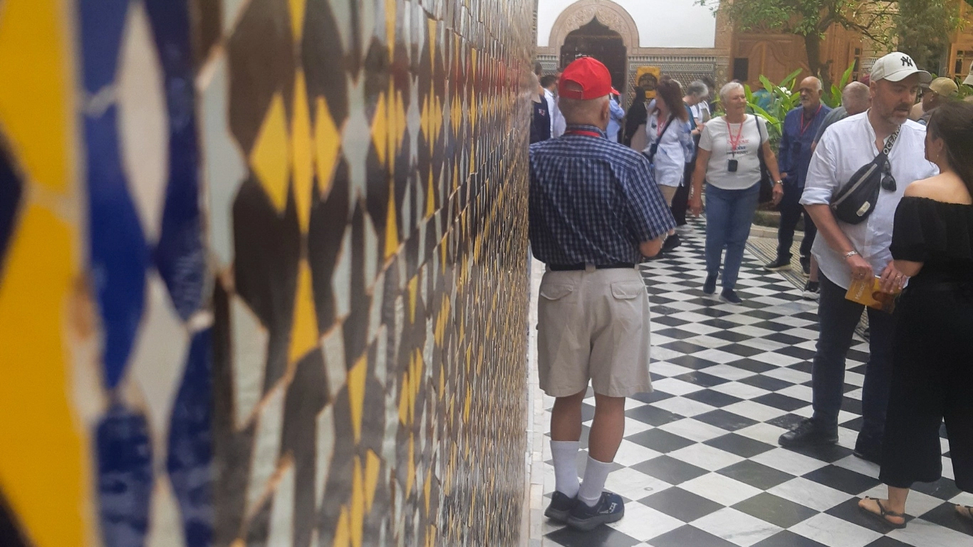 Visitors exploring the vibrant mosaic tilework and traditional courtyard of Dar El Bacha Palace in Marrakech.
