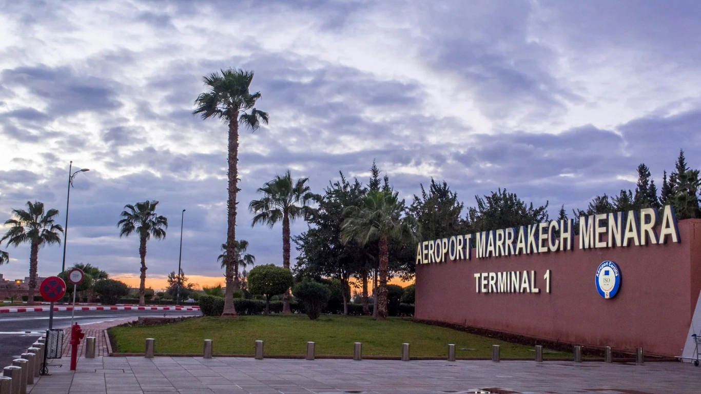 Marrakech Menara Airport Terminal 1 sign at sunrise, surrounded by palm trees, serving as a gateway to the city center.