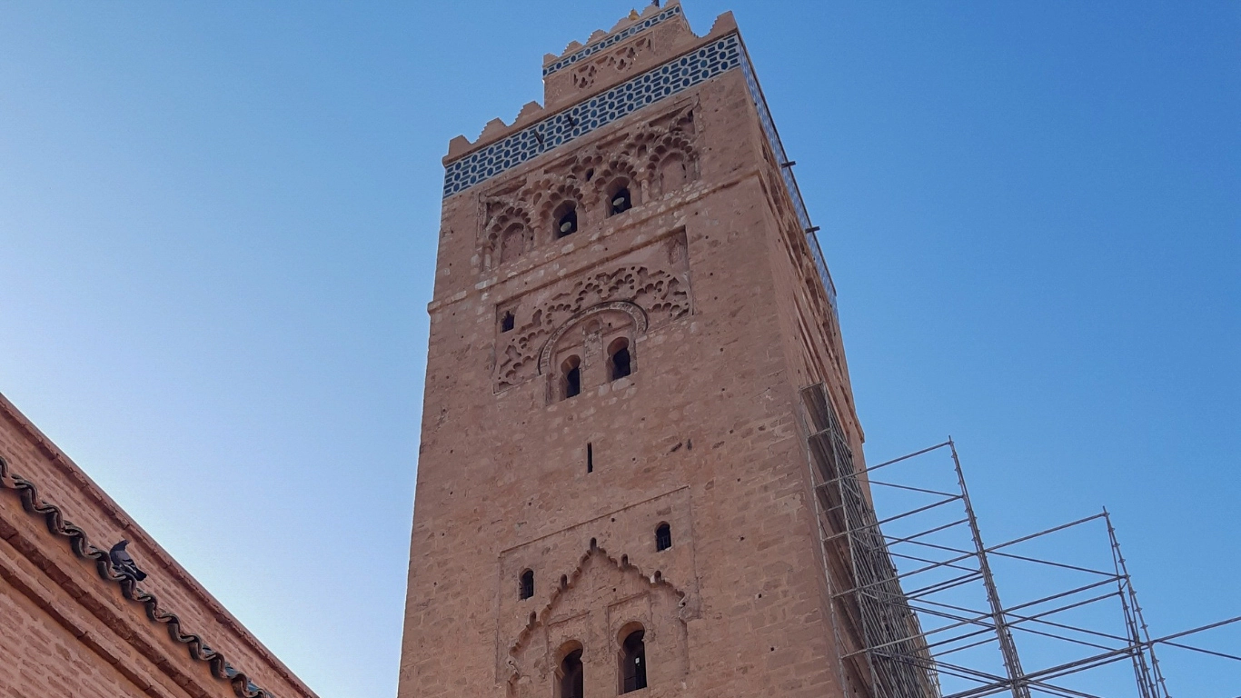Iconic minaret of Koutoubia Mosque in Marrakech, Morocco, with traditional Moorish architecture and clear blue sky.
