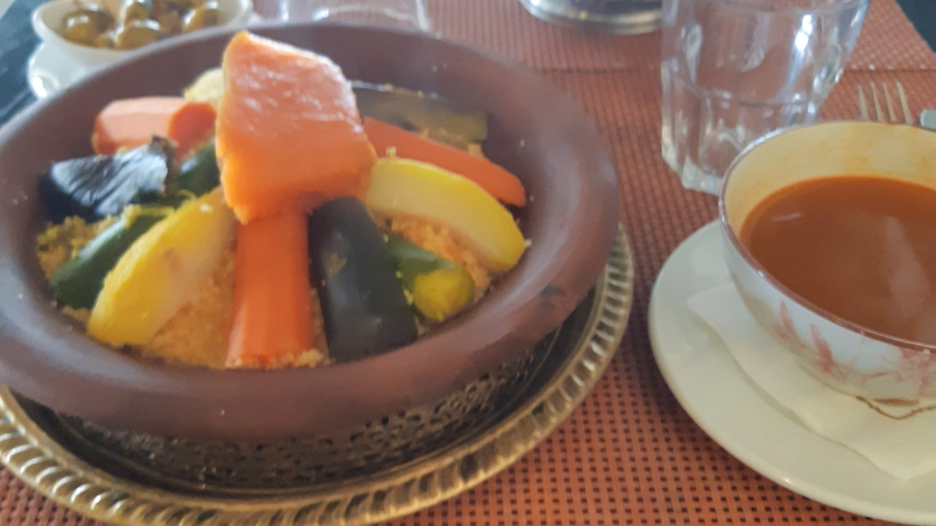 Delicious plate of couscous with vegetables served at Argan Cafe in Marrakech, accompanied by tea and bread