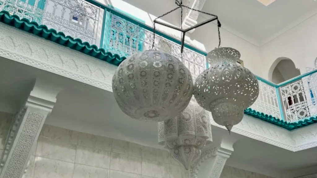 Beautiful interior of Riad 1001 Couleurs in Marrakech featuring ornate Moroccan lanterns and traditional architectural details.