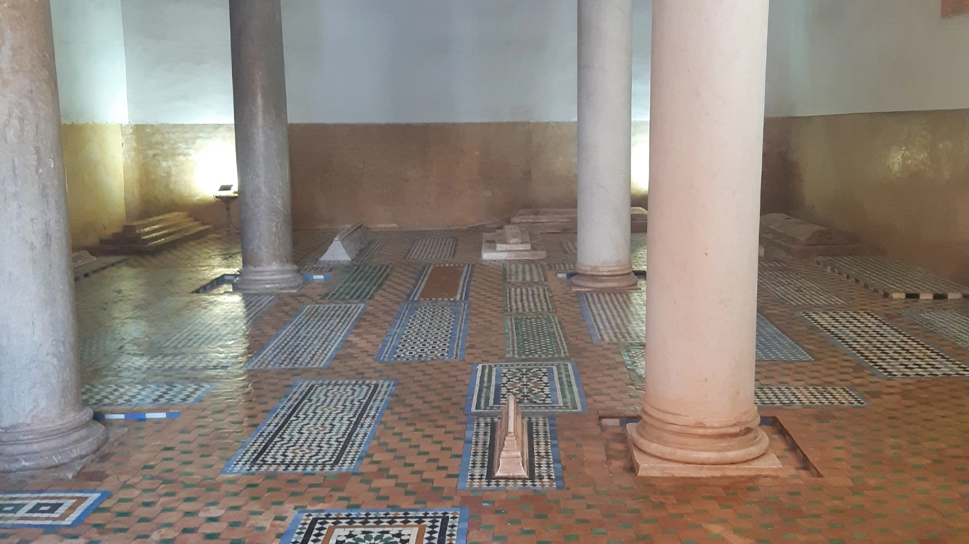Interior view of the Saadian Tombs in Marrakech, featuring ornate mosaic-tiled graves and marble columns in a historic chamber.

