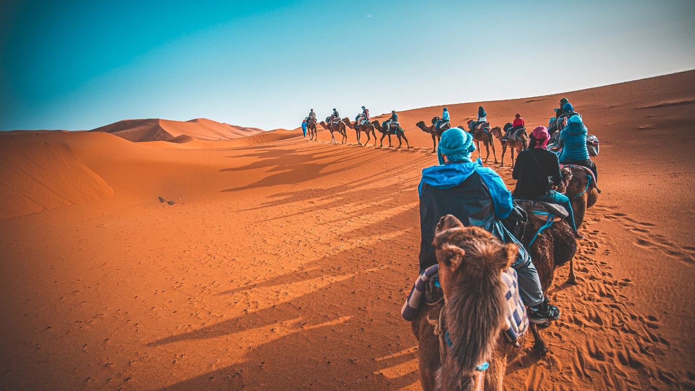 Man in traditional attire walking on a carpet in the Merzouga Desert camp during a 3-day tour from Marrakech