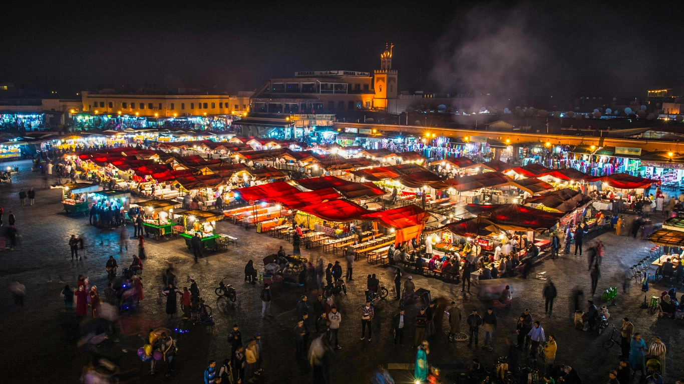 A vibrant night scene of food stalls and bustling crowds in Marrakech's night market