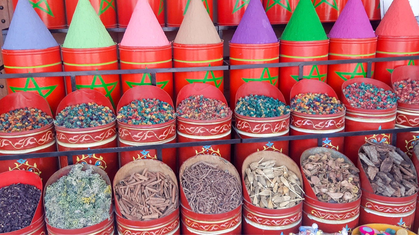 Vibrant display of colorful spices in conical shapes at a Marrakech market, showcasing a variety of flavors and aromas.