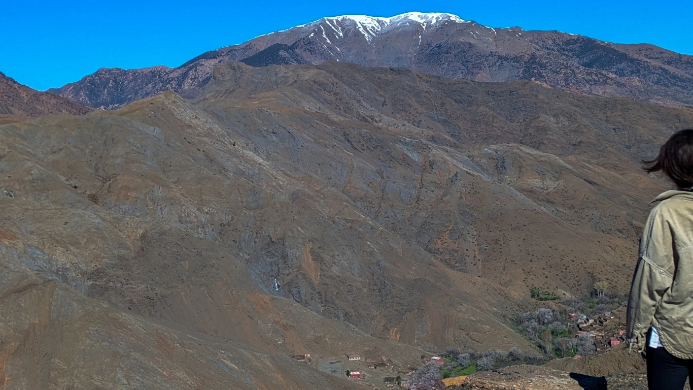 Traveler overlooking the winding Tizi n'Tichka road and High Atlas mountains during a Marrakech to Merzouga trip.