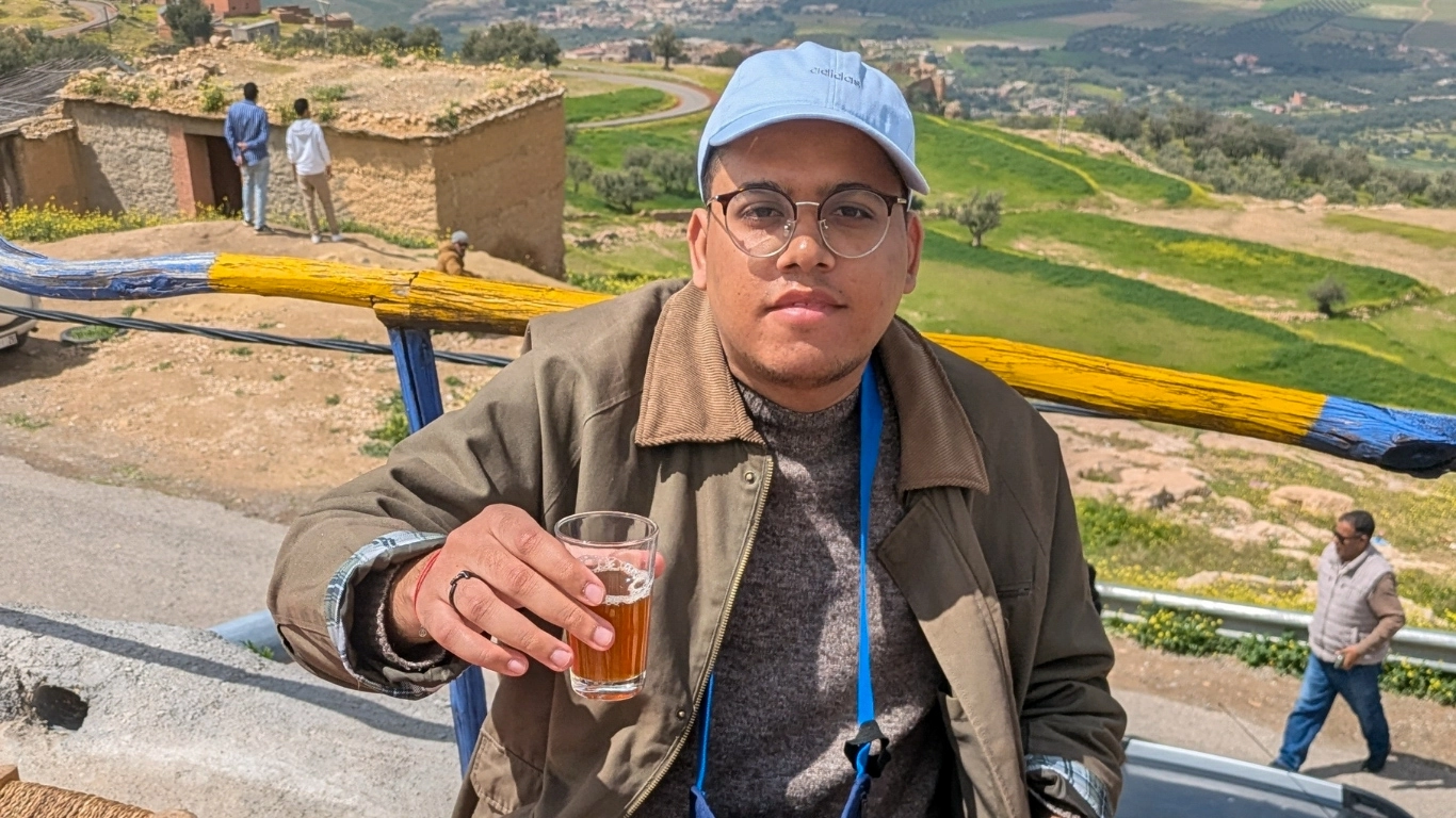 Traveler holding a glass of traditional five-herb tea at a Berber women's cooperative near Kik Plateau, Marrakech.