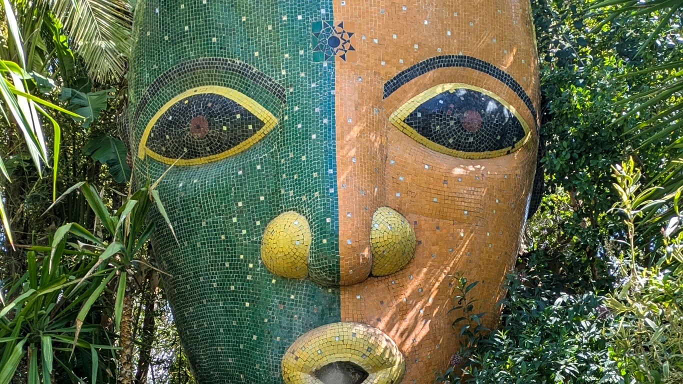 Large mosaic face sculpture by André Heller surrounded by tropical plants at Anima Garden near Marrakech